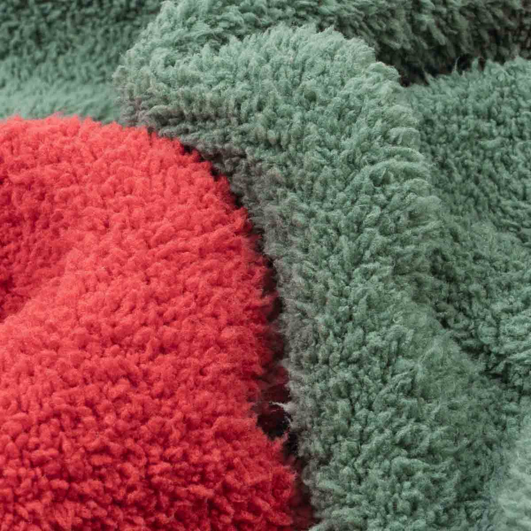 Close-up of fuzzy fabric in two colors: a bright red section and a muted sage green section