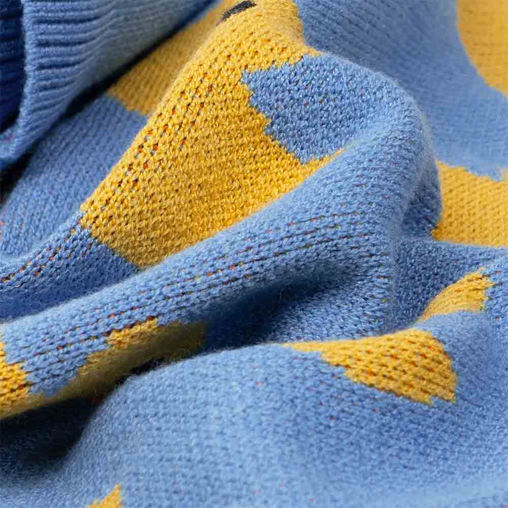 Close-up of soft blue knit fabric with vibrant yellow duck print detail, highlighting the cozy texture of the dog sweater.