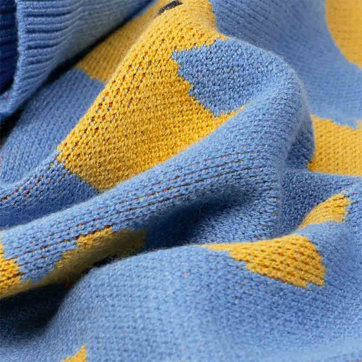 Close-up of soft blue knit fabric with vibrant yellow duck print detail, highlighting the cozy texture of the dog sweater.