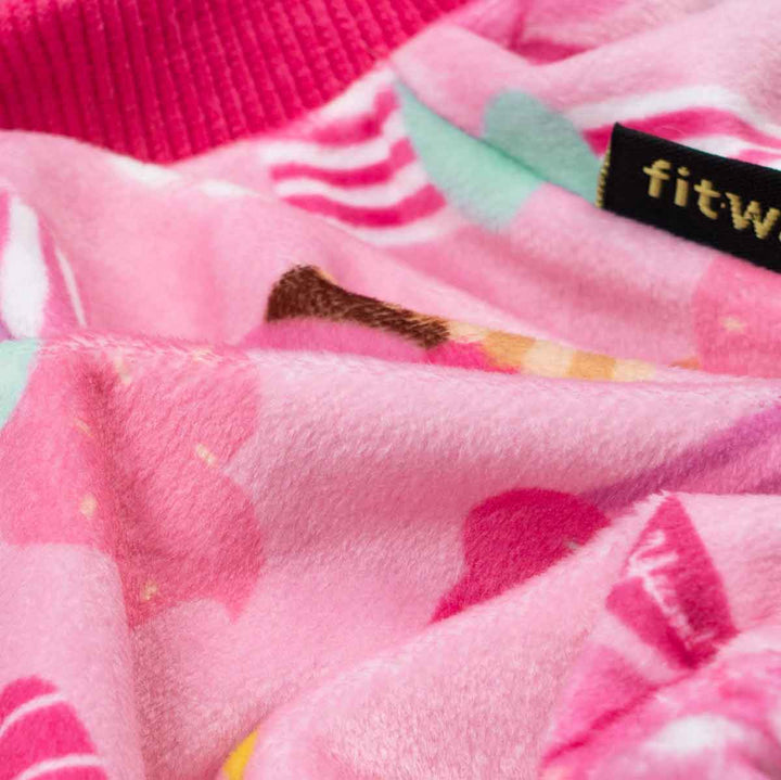 Soft pink dog pajamas with a cupcake and frosting pattern, featuring a "Sweet Treat" detail and a "fitwarm" tag.