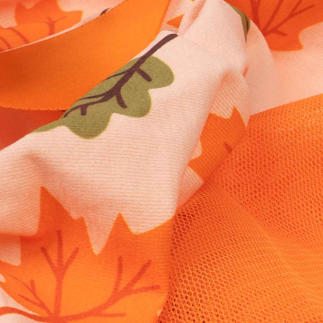 Close-up of a fabric product showing a pattern of orange maple leaves on a light peach background, alongside a solid bright orange mesh section