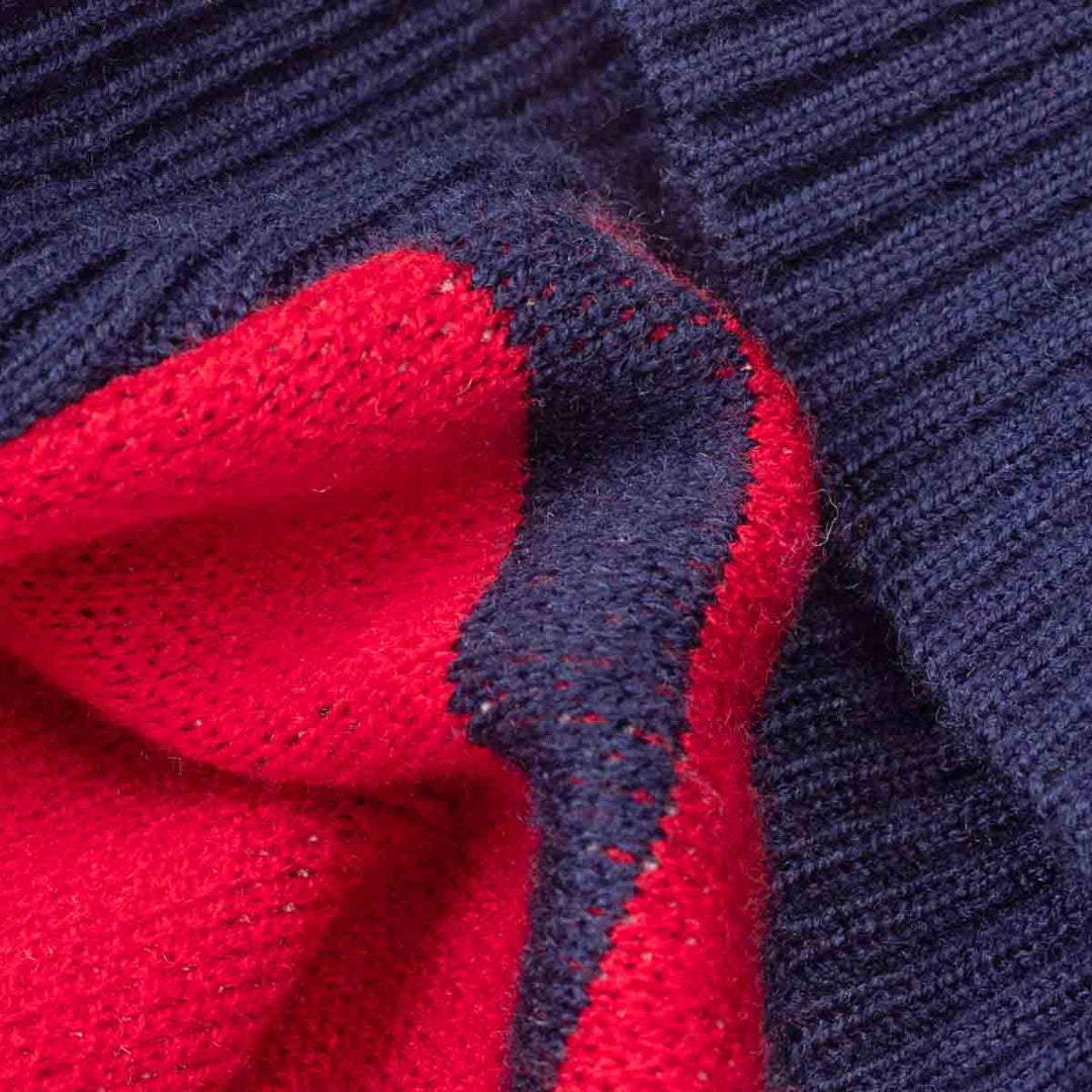 Close-up of a ribbed knit fabric of dog winter sweaters in navy blue and bright red, showing the texture and color blocking of the material