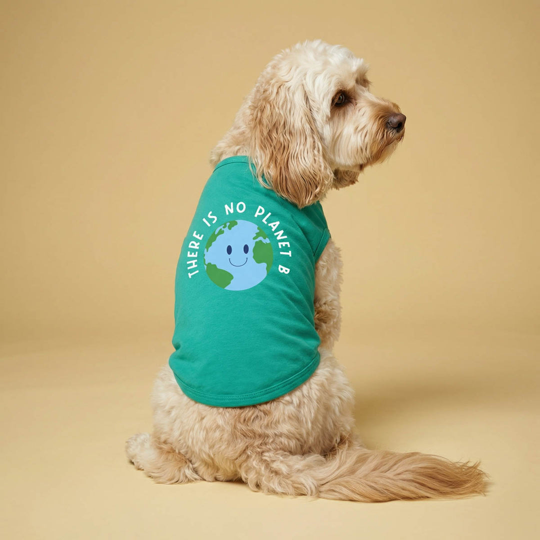 Dog wearing a green sleeveless dog tshirt with an environmental 'There is no planet B' lettering on a beige background