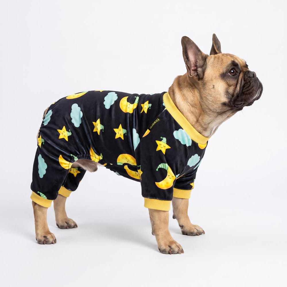 French Bulldog wearing a black long-sleeve pajama for dogs with a yellow, blue, and yellow-green space-themed print of stars, moons, and clouds
