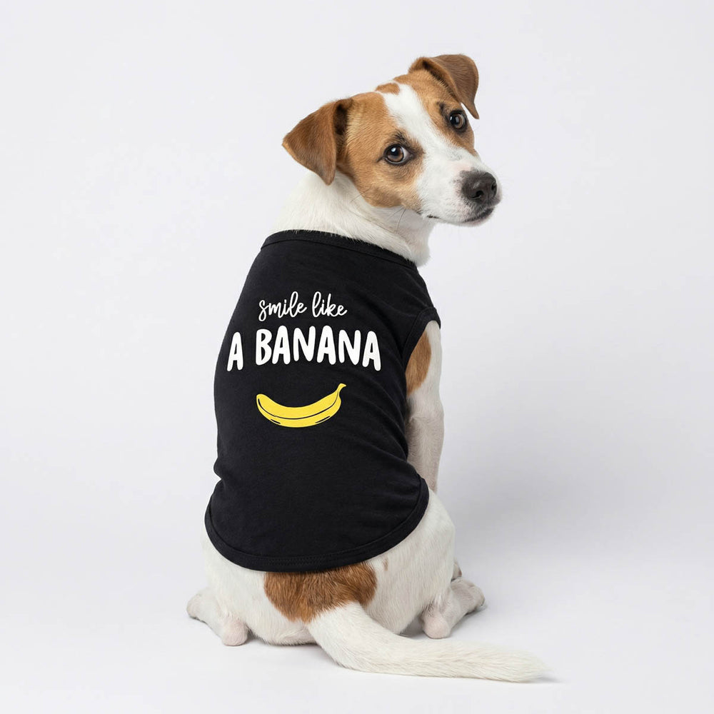 Dog wearing a black sleeveless shirt for dog with 'Smile Like A Banana' lettering and banana print on a white background