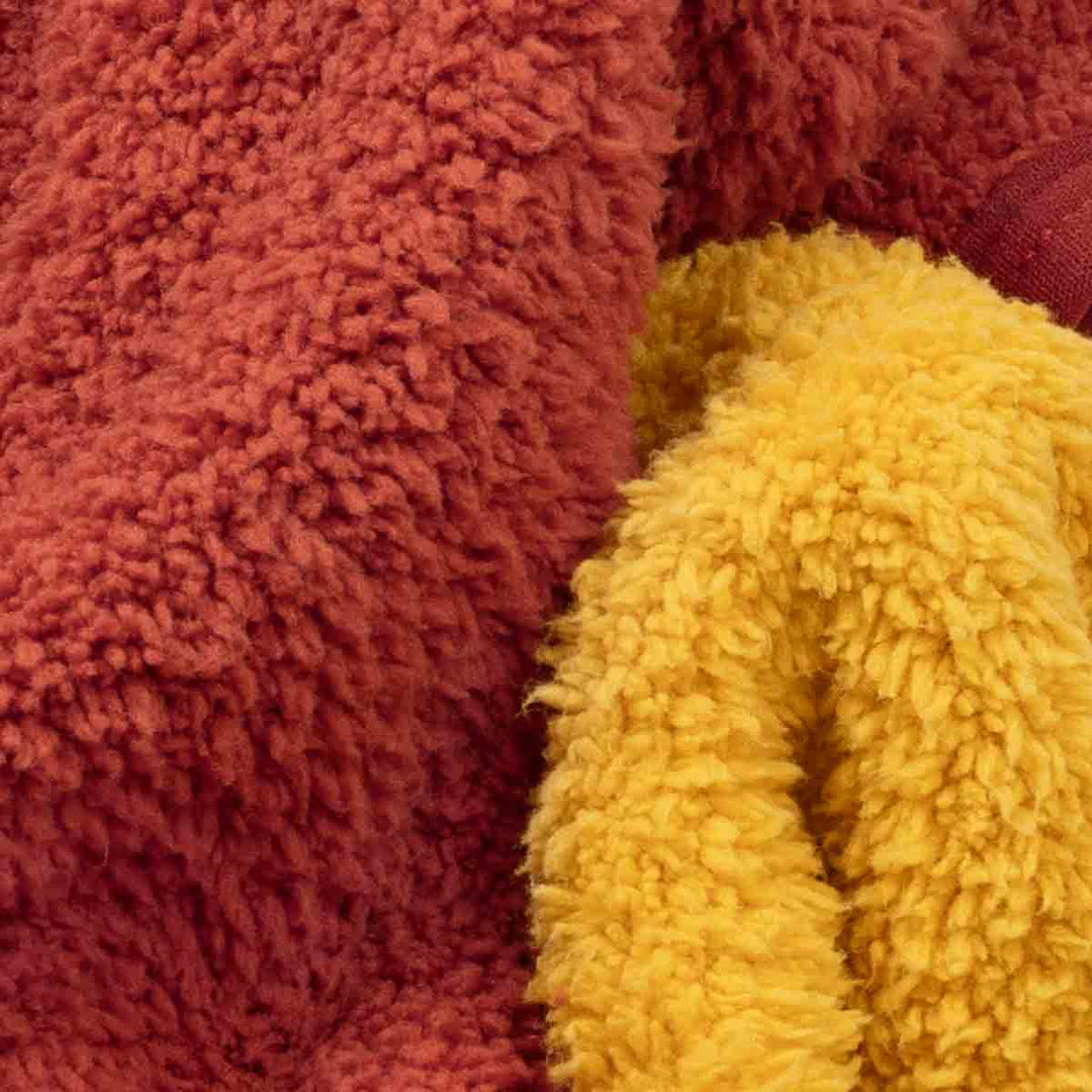 Close-up of plush sherpa fabric in two colors: a rust red section on the left and a mustard yellow section on the right