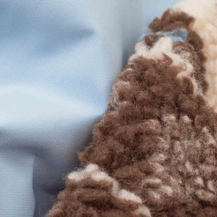 Close-up of a textured brown and cream chunky knit fabric with a light blue layer