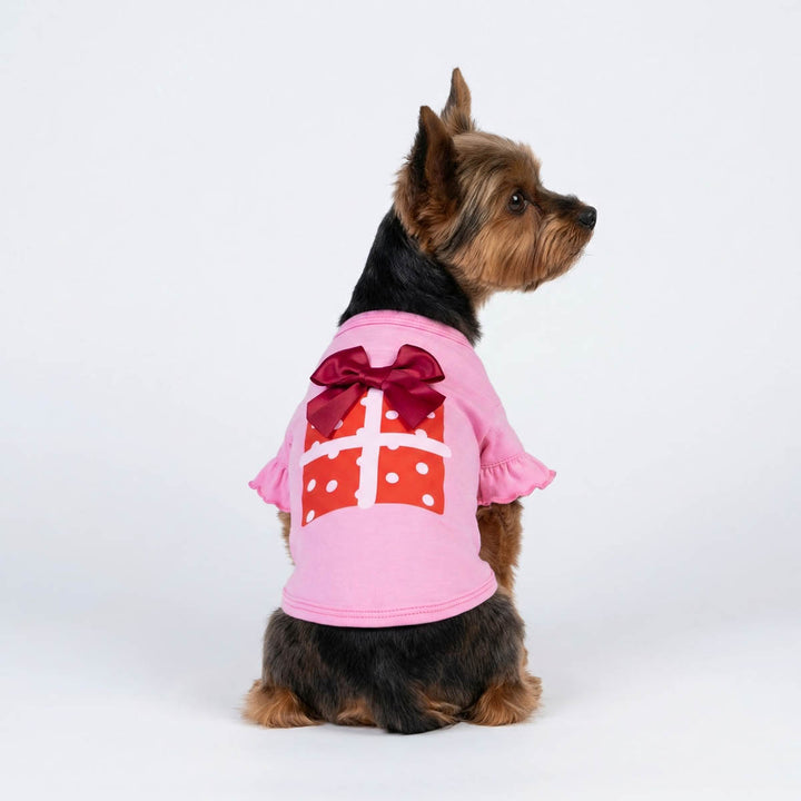 Pink dog shirt with gift box print, red bow, and ruffled sleeves for parties.