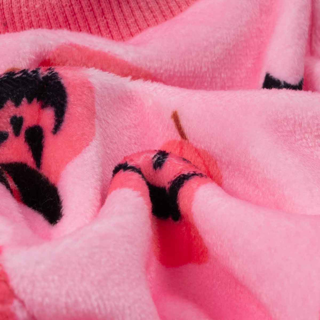 Close-up of soft pink dog pajamas fabric, showing plush polyester, stretchy collar, and Halloween pumpkin patterns.