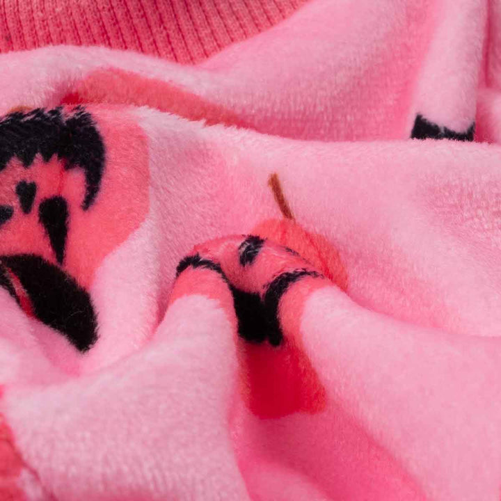 Close-up of soft pink dog pajamas fabric, showing plush polyester, stretchy collar, and Halloween pumpkin patterns.
