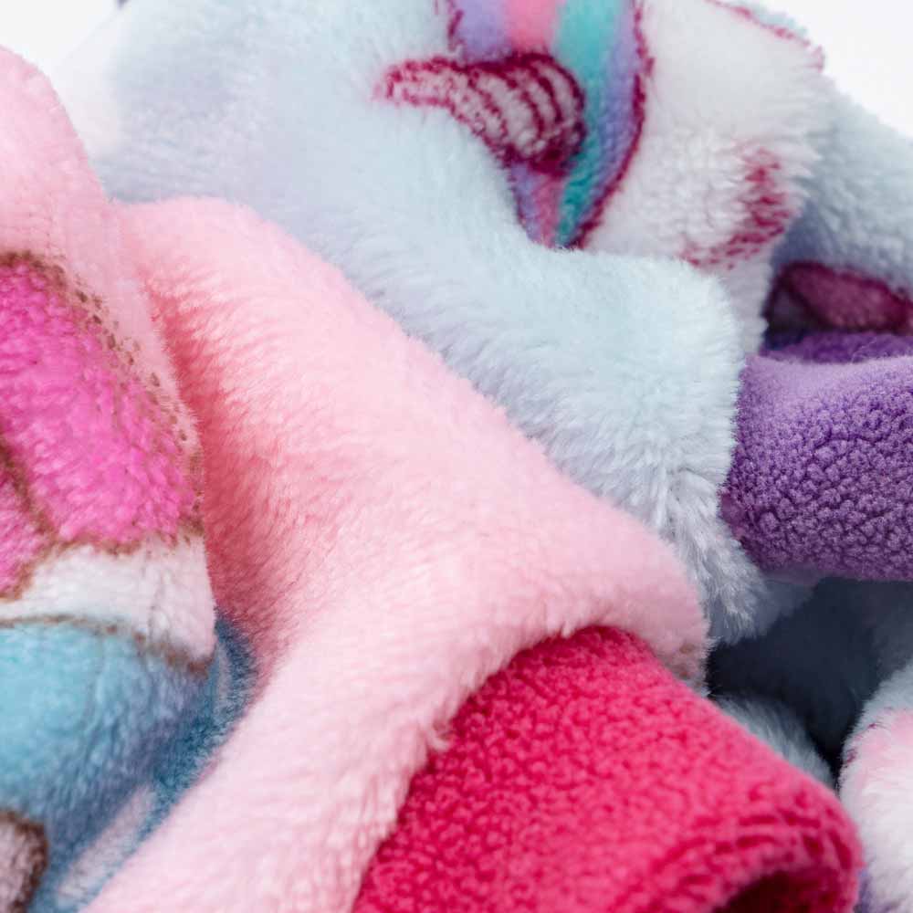 Plush fleece dog sweater fabric close up: pastel pink, blue, purple. Unicorn/cupcake patterns, cozy texture detail.