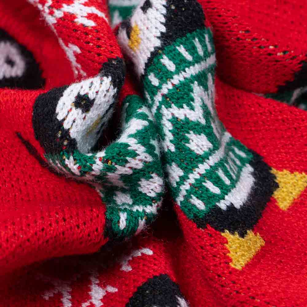 Close-up of soft knit dog sweater fabric with penguin and snowflake pattern.