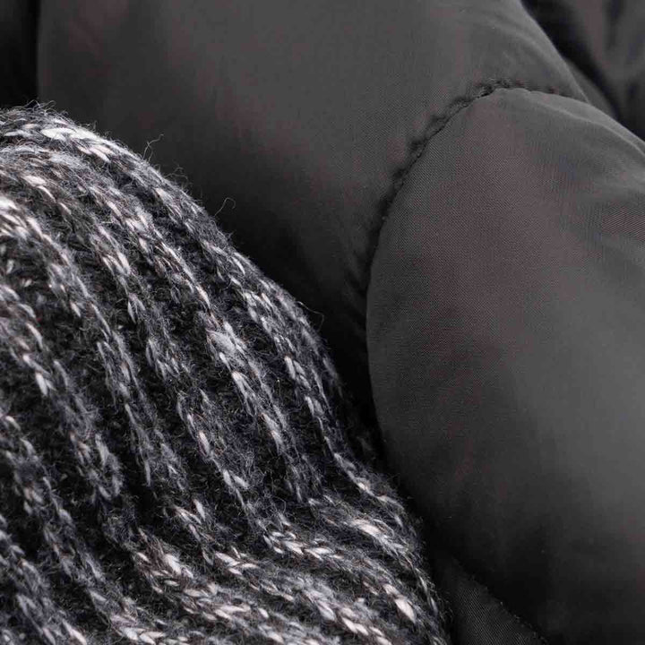 Close-up of reversible dog coat: black quilted side contrasts with marled grey knit fabric, showcasing textures.