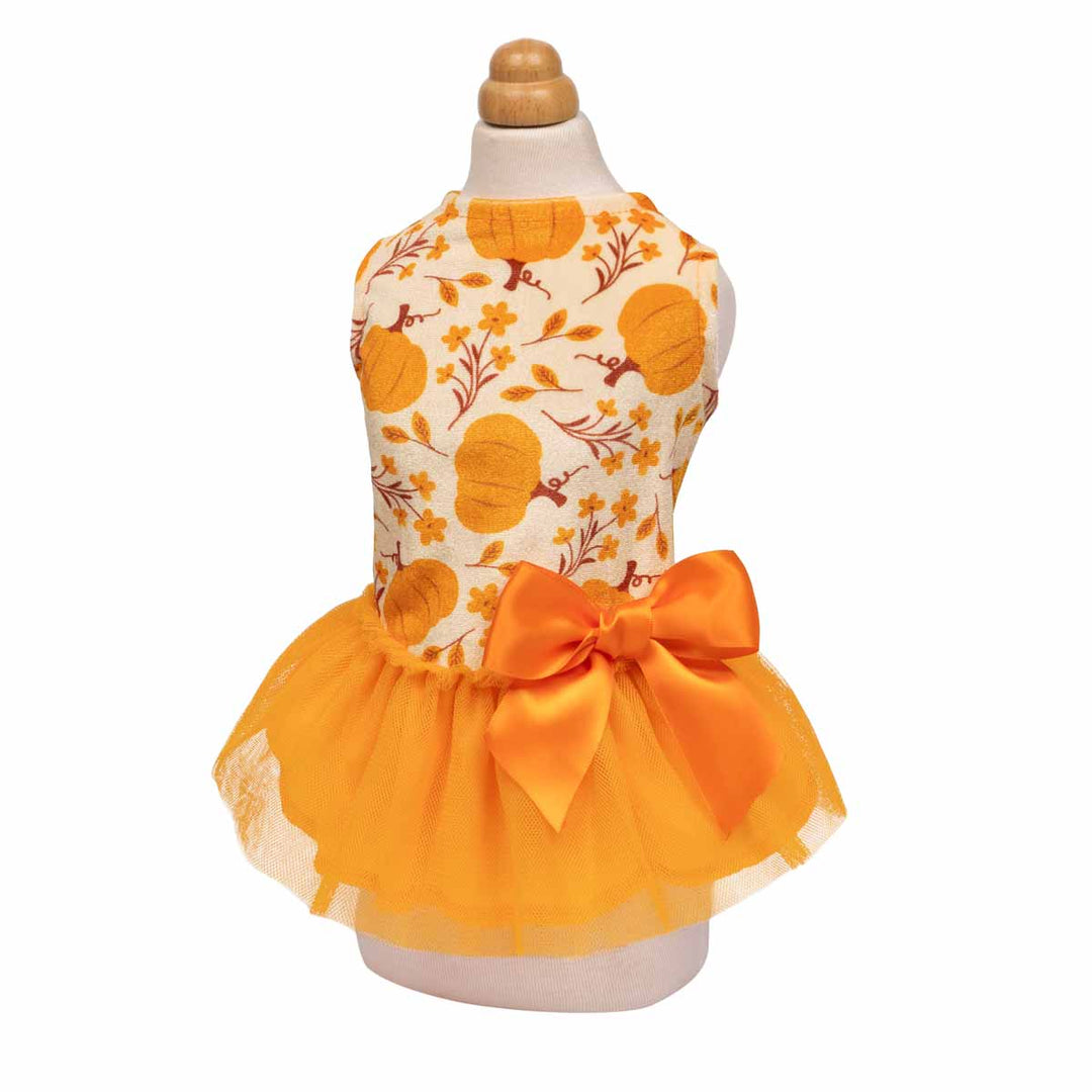Pumpkin print dog dress with orange bow and tulle skirt, perfect for fall photoshoots.