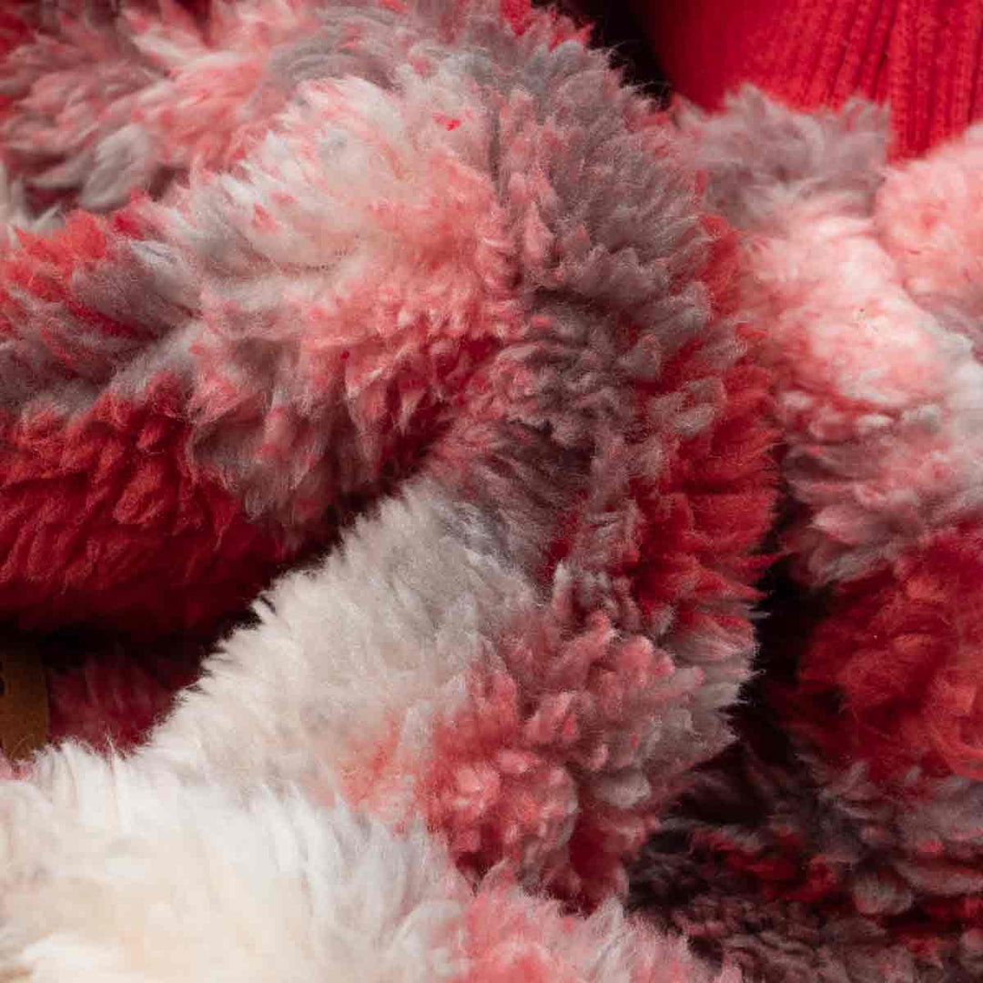 Holiday-ready dog wearing red plaid fleece pajamas in warm lighting