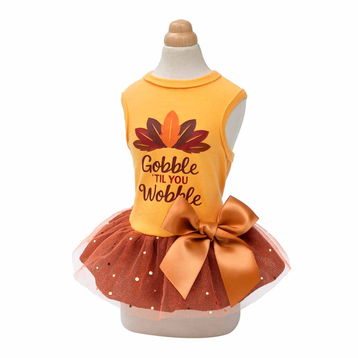 Mannequin wearing orange Thanksgiving dog dress with feather graphic and glittery brown bow skirt.