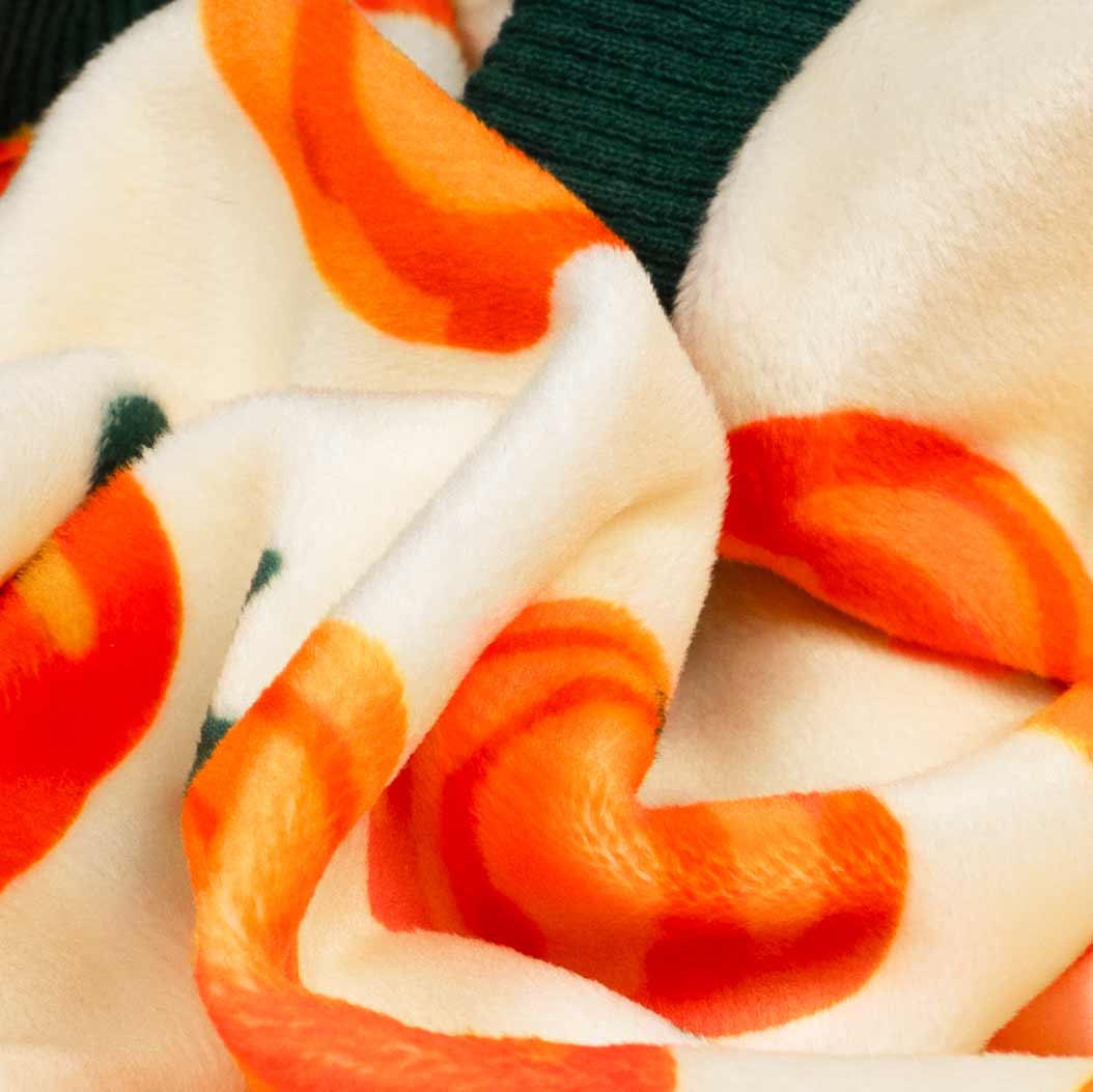 Close-up of soft fleece fabric with pumpkin print on cozy dog pajamas.