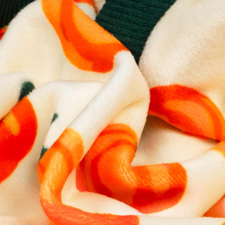 Close-up of soft fleece fabric with pumpkin print on cozy dog pajamas.