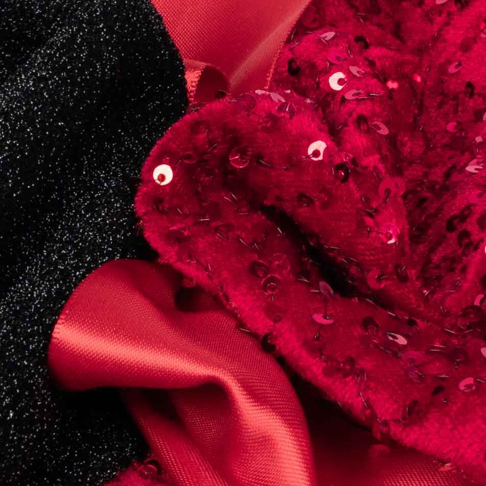 Detailed view of black glitter fabric and red sequin skirt from a festive dog dress.