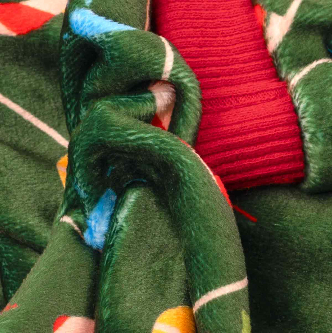 Close-up of green dog pajamas fabric showing soft velvet texture with red ribbed trim.