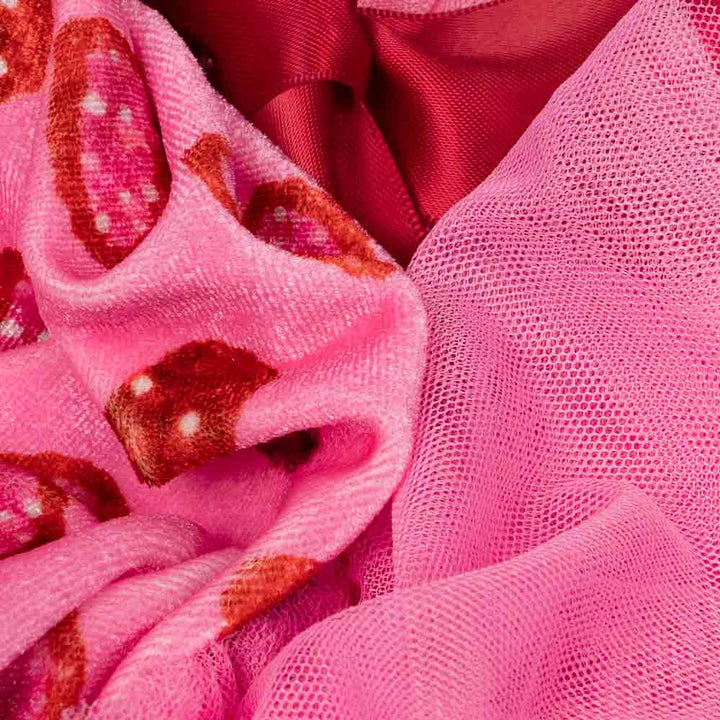 Fabric detail of pink dog dress showing soft velvet heart patterns and mesh tulle layers.