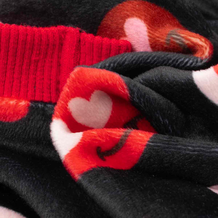 Close-up of cozy heart-pattern fabric on black dog pajamas.