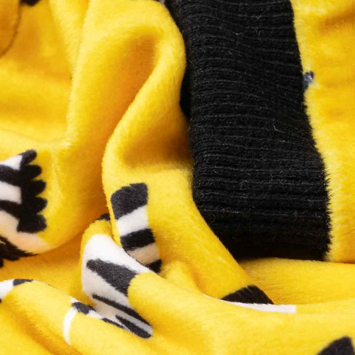Close-up of yellow dog pajamas showing soft fleece texture with zebra print and black ribbed cuff.