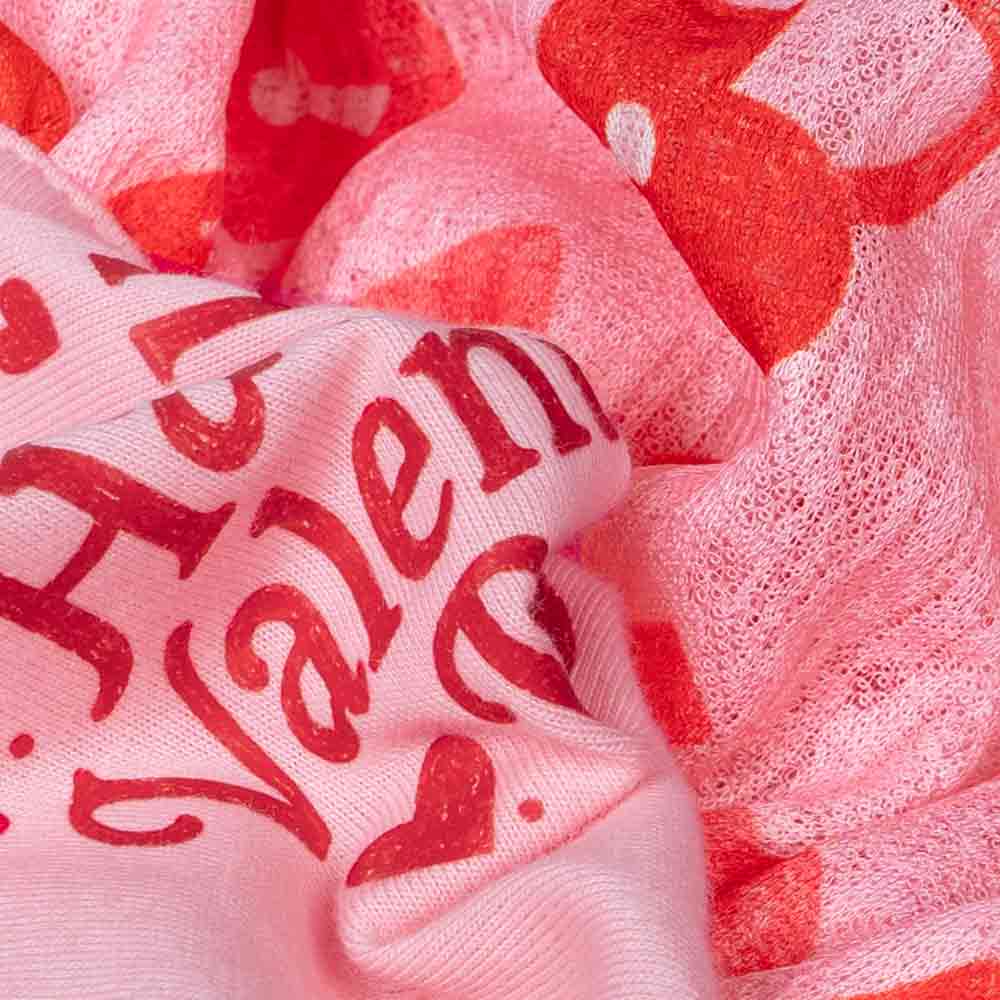 Close-up view of a pink Valentine-themed dog dress with red heart and lock patterns.