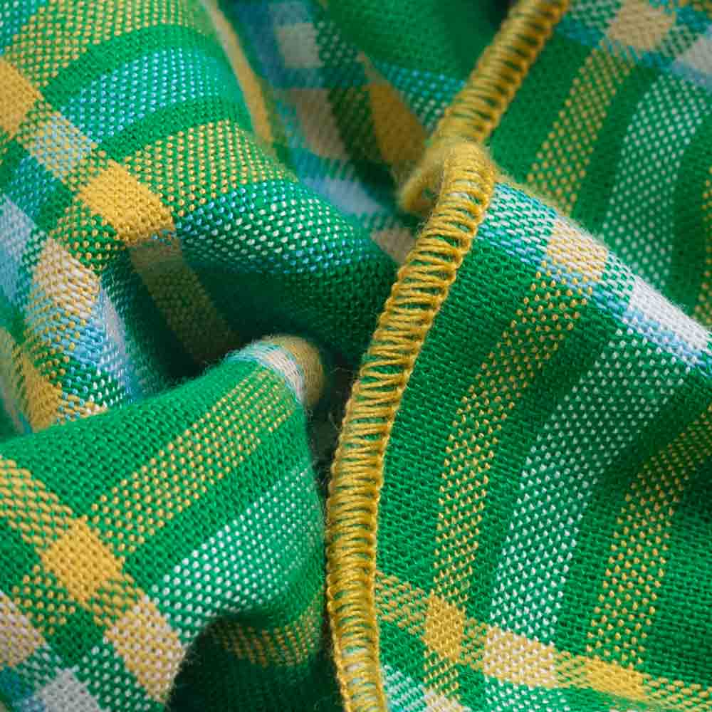 Close-up of green and yellow checkered dog dress fabric with a textured pattern.