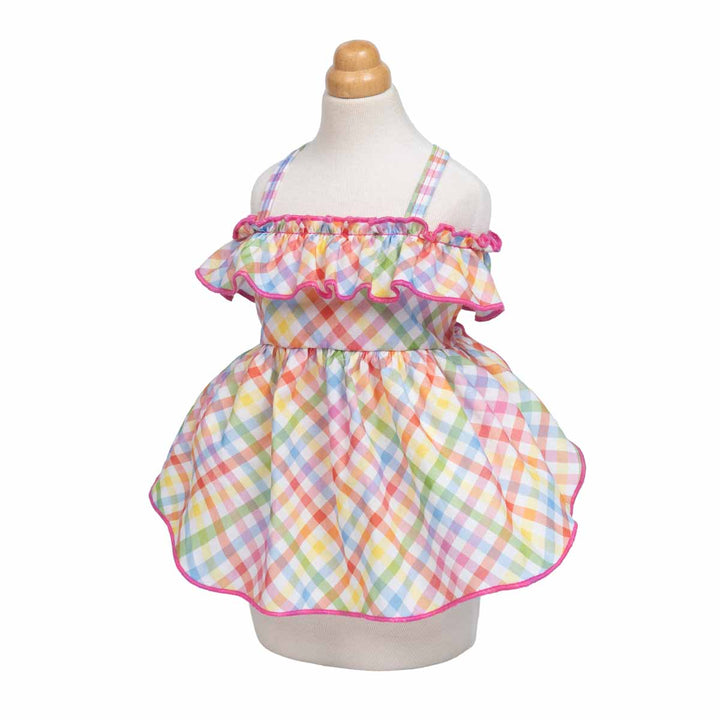 A colorful dog dress featuring a pastel plaid pattern with a ruffled neckline and hem. The dress has pink trim and adjustable straps, perfect for a playful look on a pet.