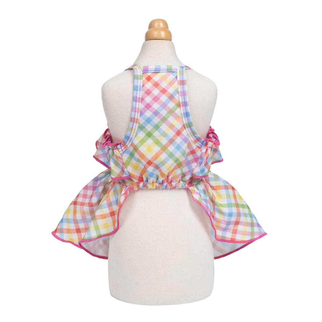 Back view of a colorful dog dress with a pastel plaid design, featuring a ruffled neckline and pink trim. The dress has adjustable straps and a gathered skirt for a festive look.