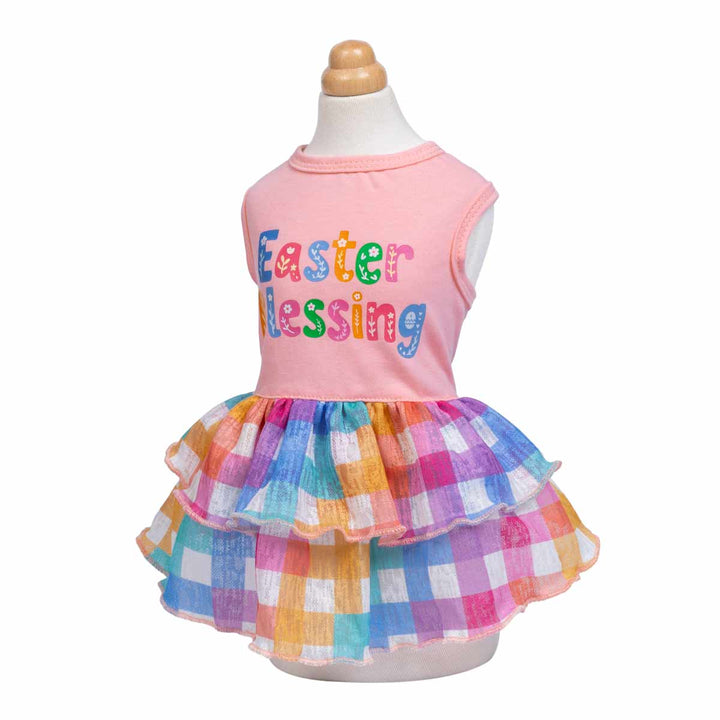A vibrant dog dress with rainbow plaid ruffled skirt and a pink top with 'Easter Blessing' design.