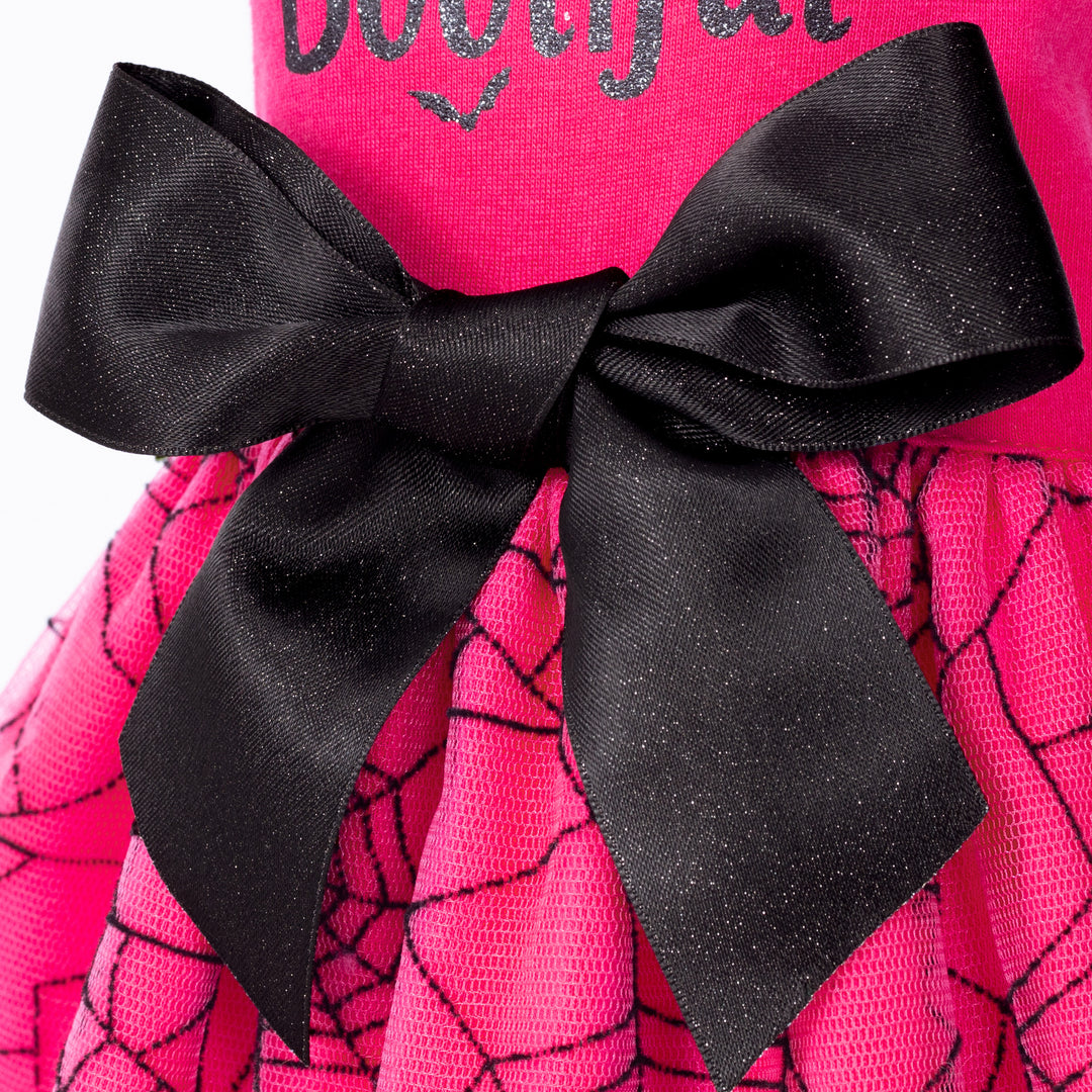 Sparkly black bow on vibrant pink Halloween dog dress with black spiderweb mesh skirt and 'Bootiful' print detail.