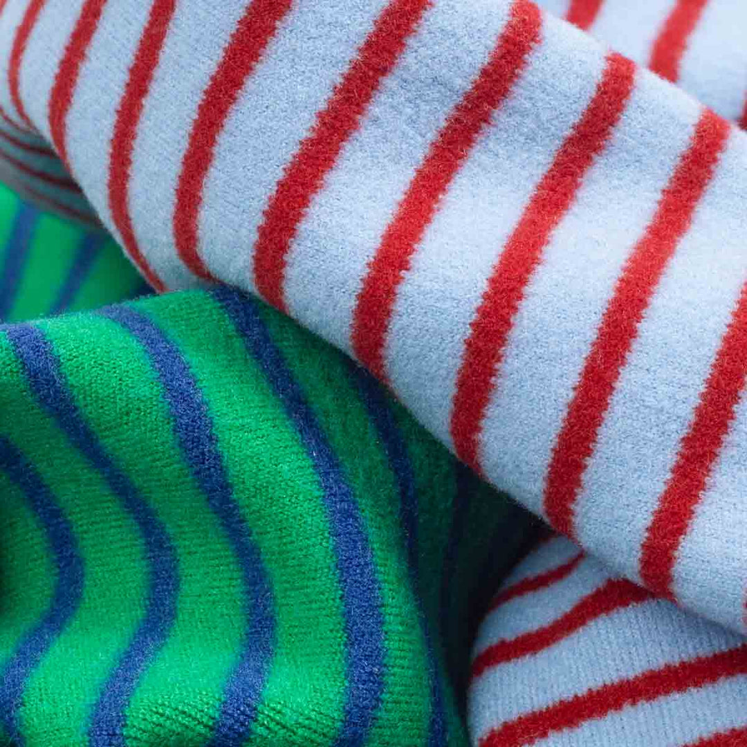 Close-up of striped lightweight velvet fabric in green-blue and red-blue colors used for dog pajamas.