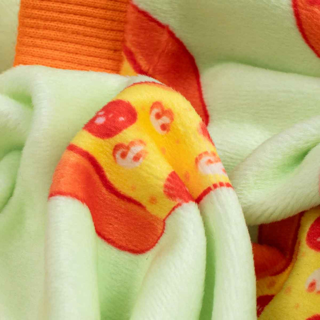 Close-up of pizza print dog pajamas fabric with orange ribbed cuff.