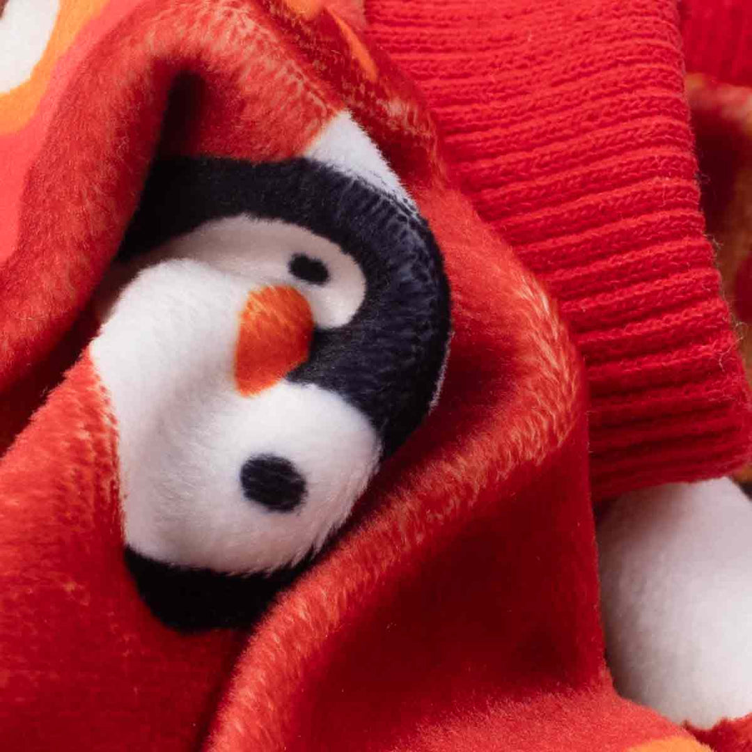 Close-up of red lightweight velvet dog pajamas showing soft texture with penguin print and ribbed cuff details.