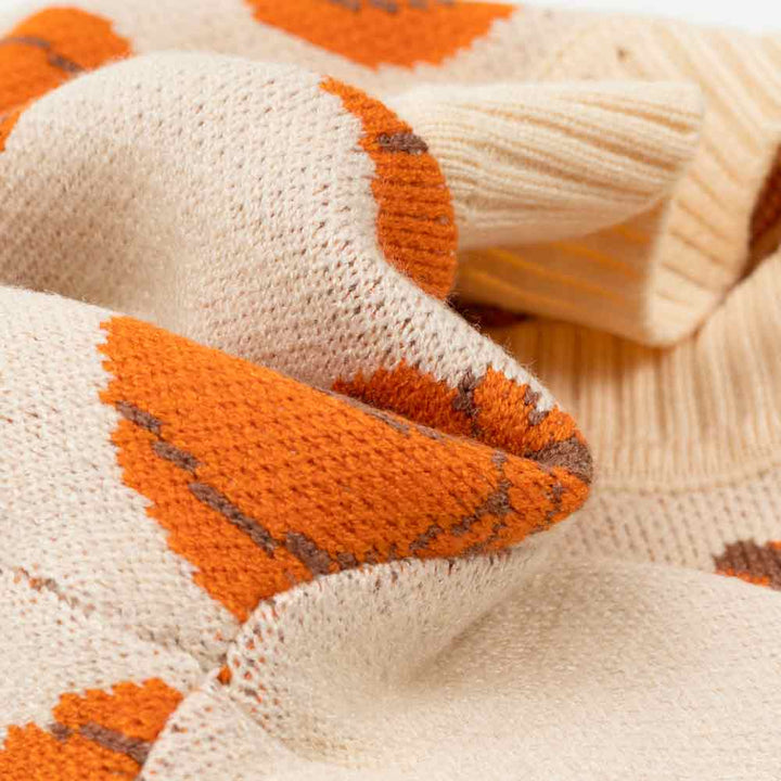 Close-up of a knitted fabric with orange and brown patterns on a beige background