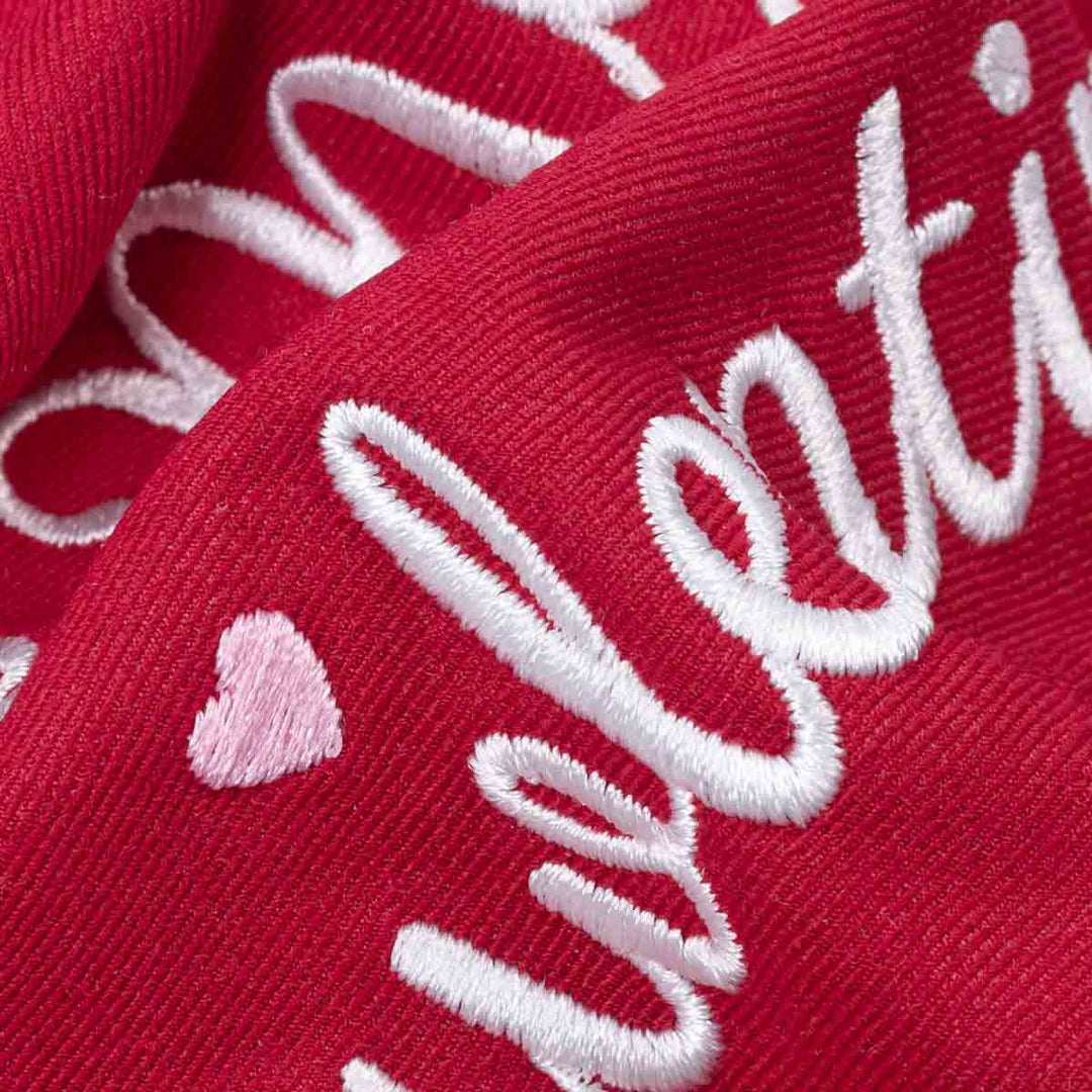 Close up of embroidered Be My Pawlentine script on red dog bandanas fabric.
