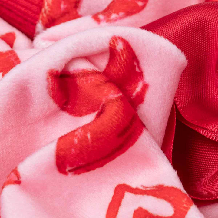 Pink heart and bow print dog pajamas fabric close-up with satin bow detail