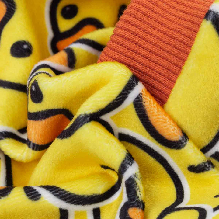 Close up of plush yellow fabric with repeating rubber duck pattern for dog pajamas.