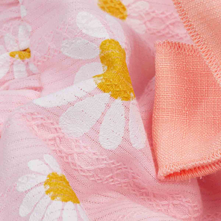Close-up of pink fabric with white daisy flowers and yellow centers