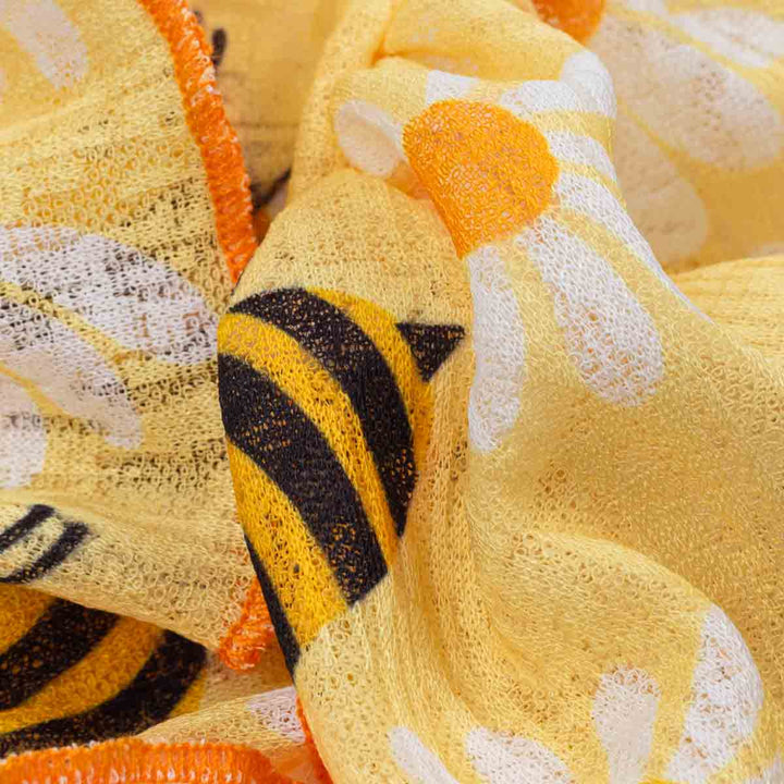 Close-up of yellow textured fabric with bee and flower patterns