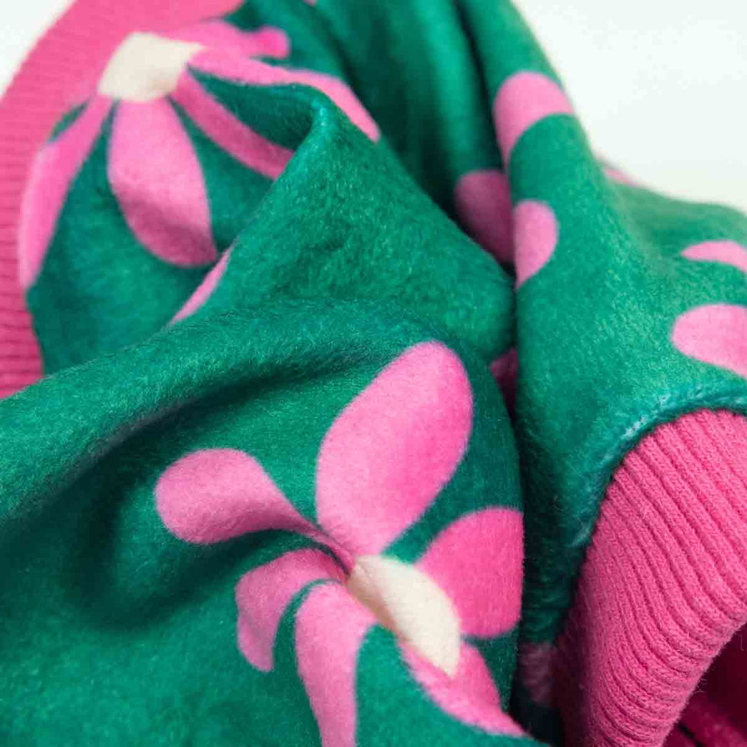 Floral dog pajamas detail. Green fabric with pink flower pattern, soft and cozy dog clothing.