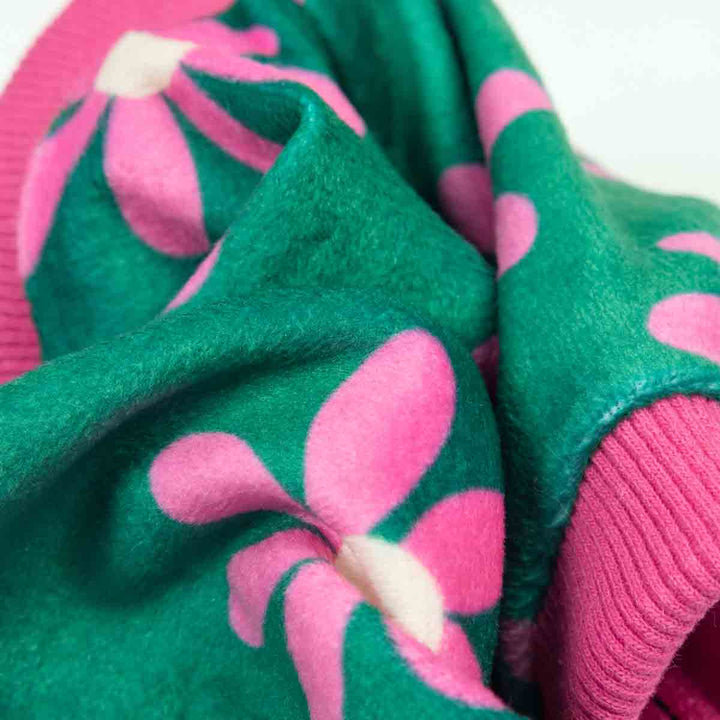 Floral dog pajamas detail. Green fabric with pink flower pattern, soft and cozy dog clothing.