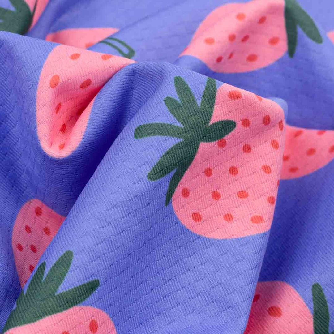 Close-up of fabric with pink strawberry pattern on a blue background