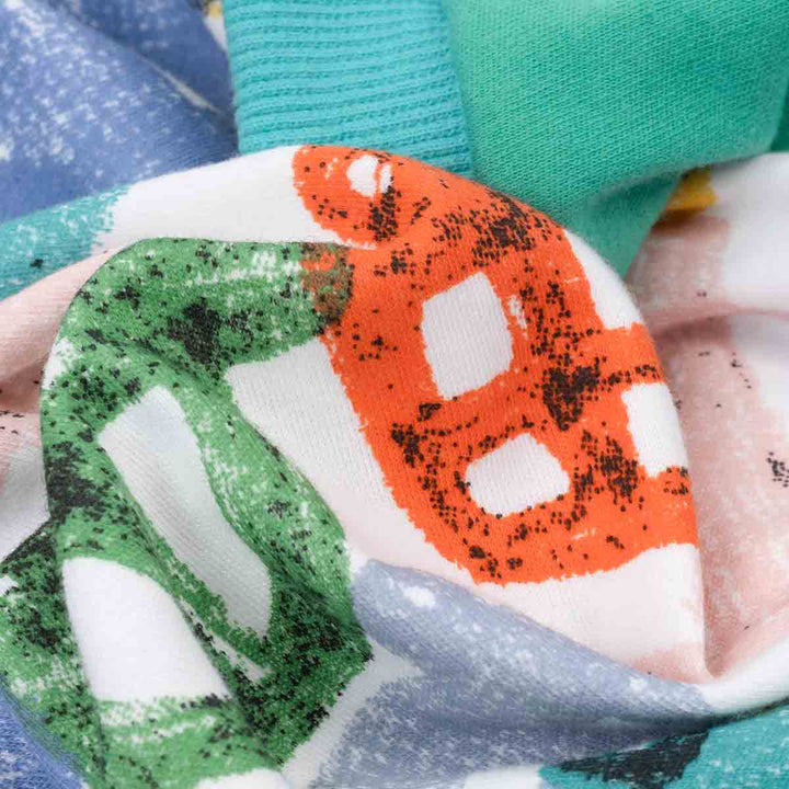 Close-up of a colorful fabric swatch with green, orange, and white pattern.
