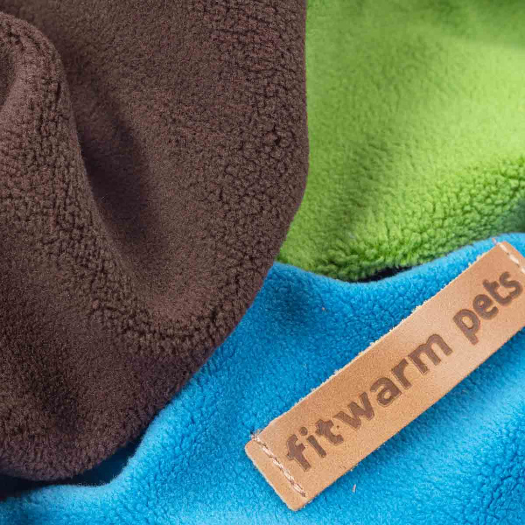 Close-up of a product with 'fitwarm pets' label on blue, green, and brown fabric