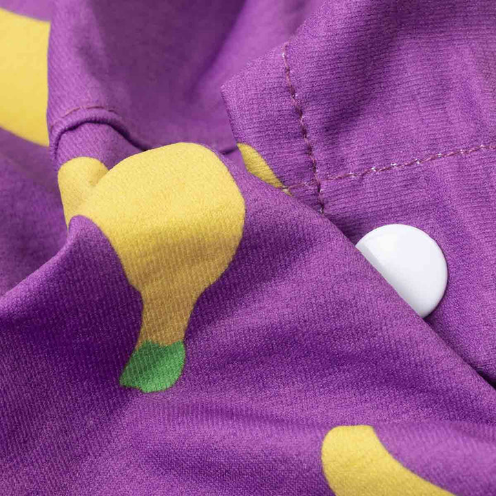 Close-up of a purple fabric with yellow banana prints and a white button.
