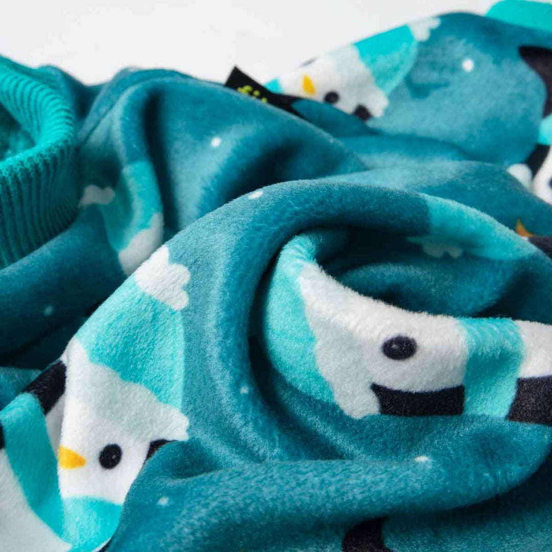 Close-up of teal blue penguin dog pajamas fabric, soft fleece, details of penguin print.