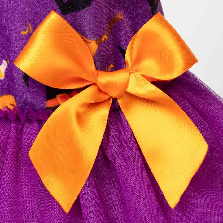 Close-up of a purple dog tulle dress with a large orange satin bow at the waist and 
